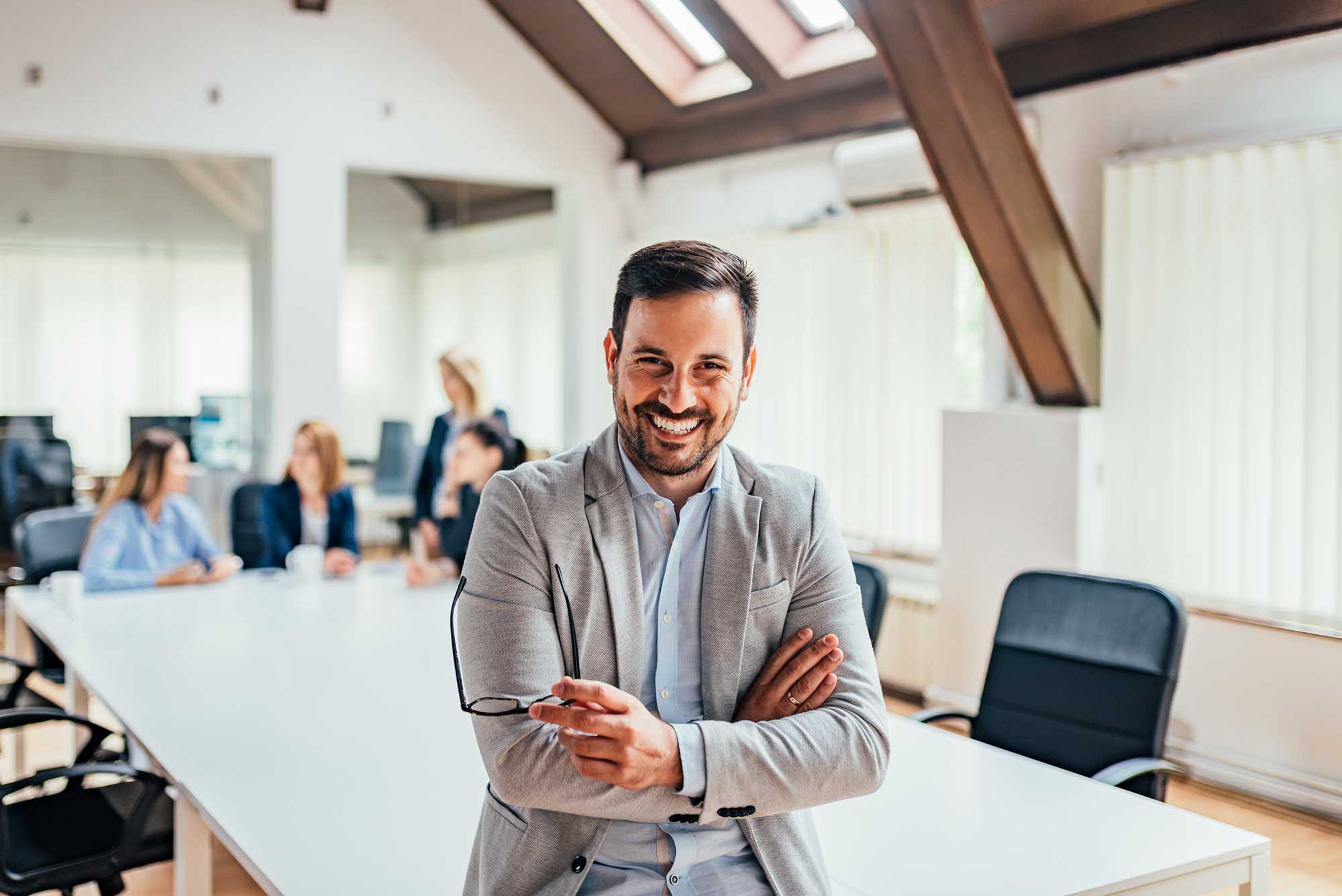 Portrait of a smiling handsome businessman with crossed arms in a meeting room.